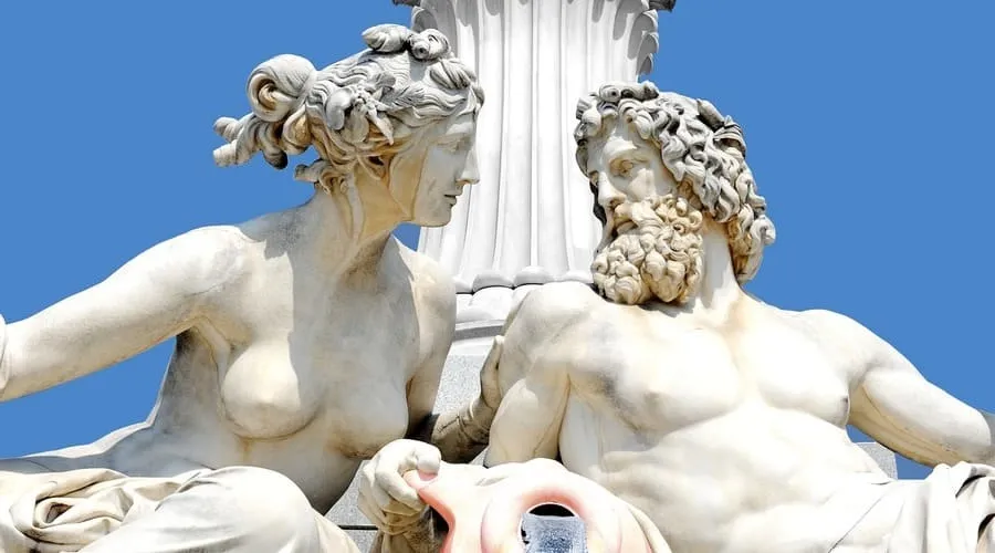 Una estatua de dos dioses griegos en estilo clásico. El hombre tiene barba y cabello rizado y está reclinado sobre una roca. La mujer está sentada junto al hombre y sostiene un jarrón. Esta imagen está relacionada con la mitología griega.